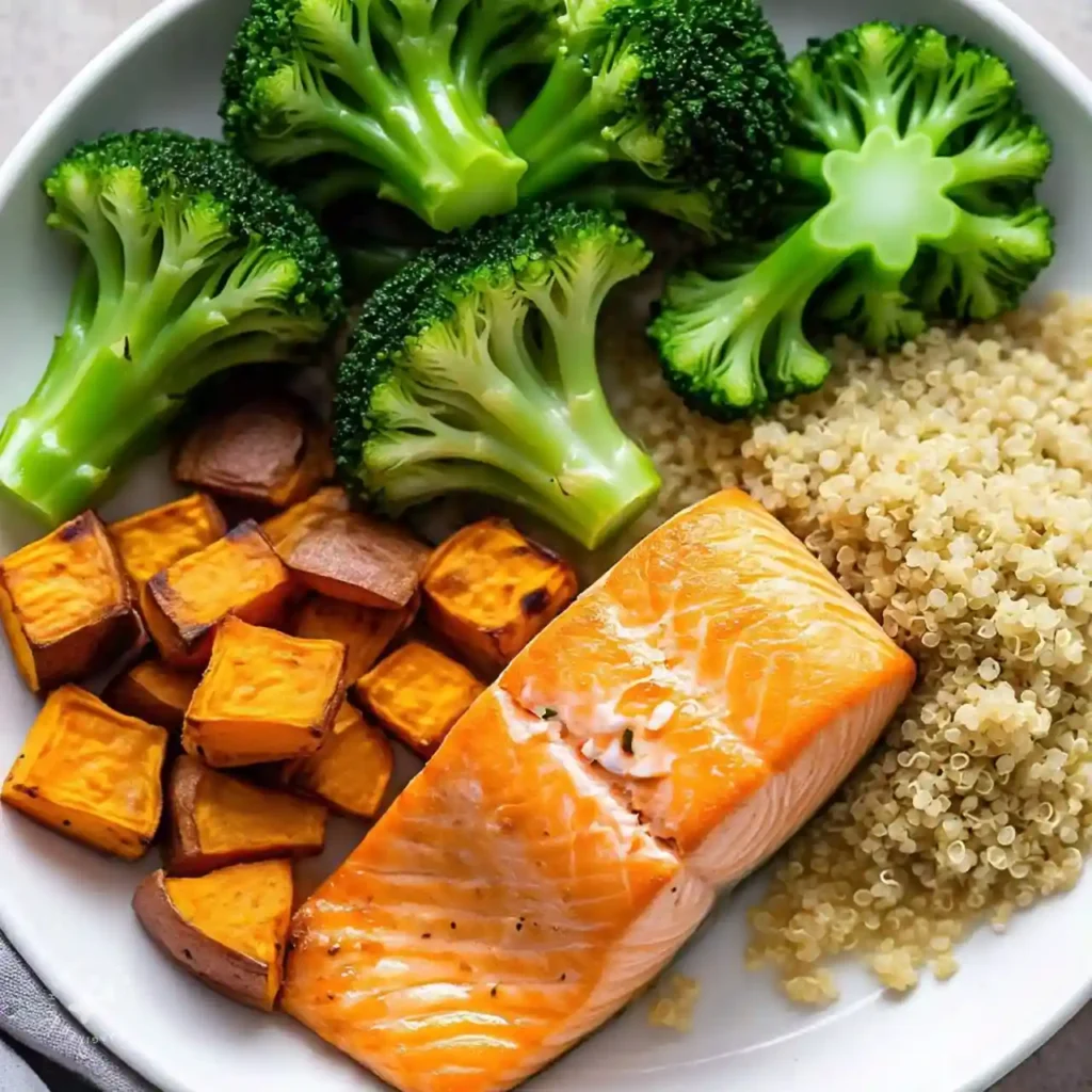 A plate of grilled salmon, quinoa, roasted sweet potatoes, and broccoli, representing a diet for hormonal health.